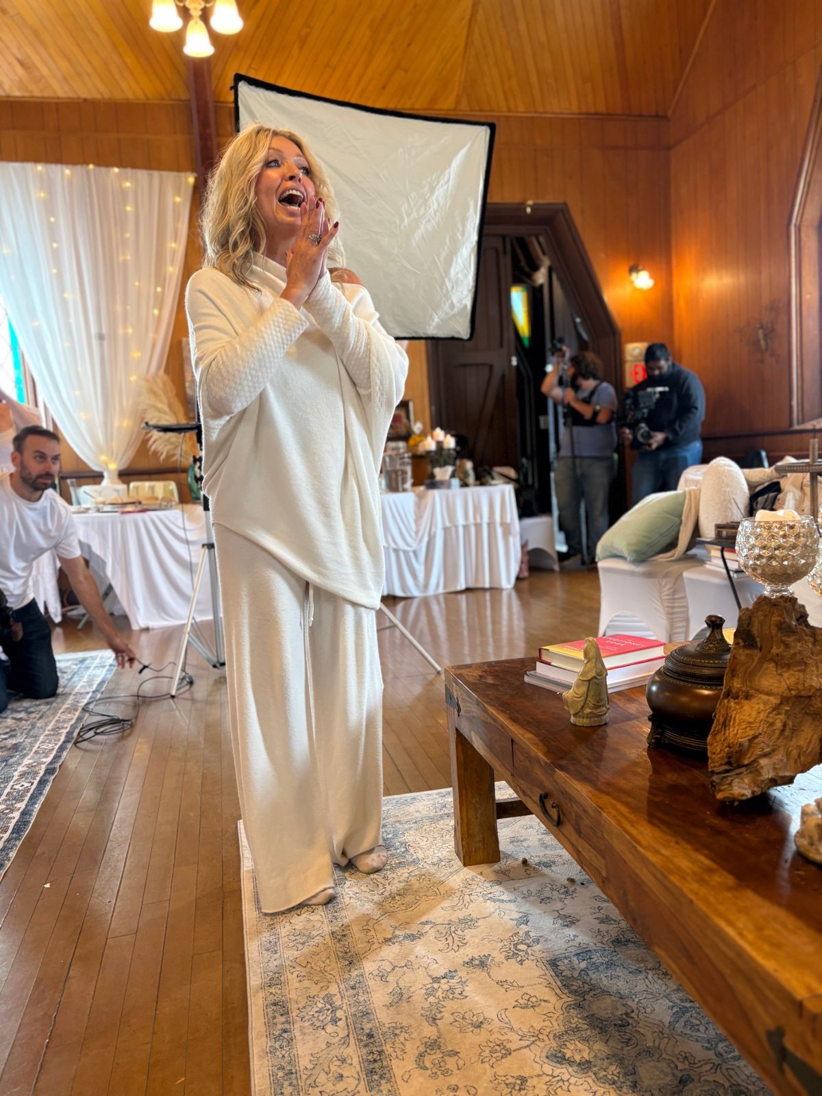 Crystal Andrus Morissette mid-moment, hands pressed together in delight, a film crew behind her.