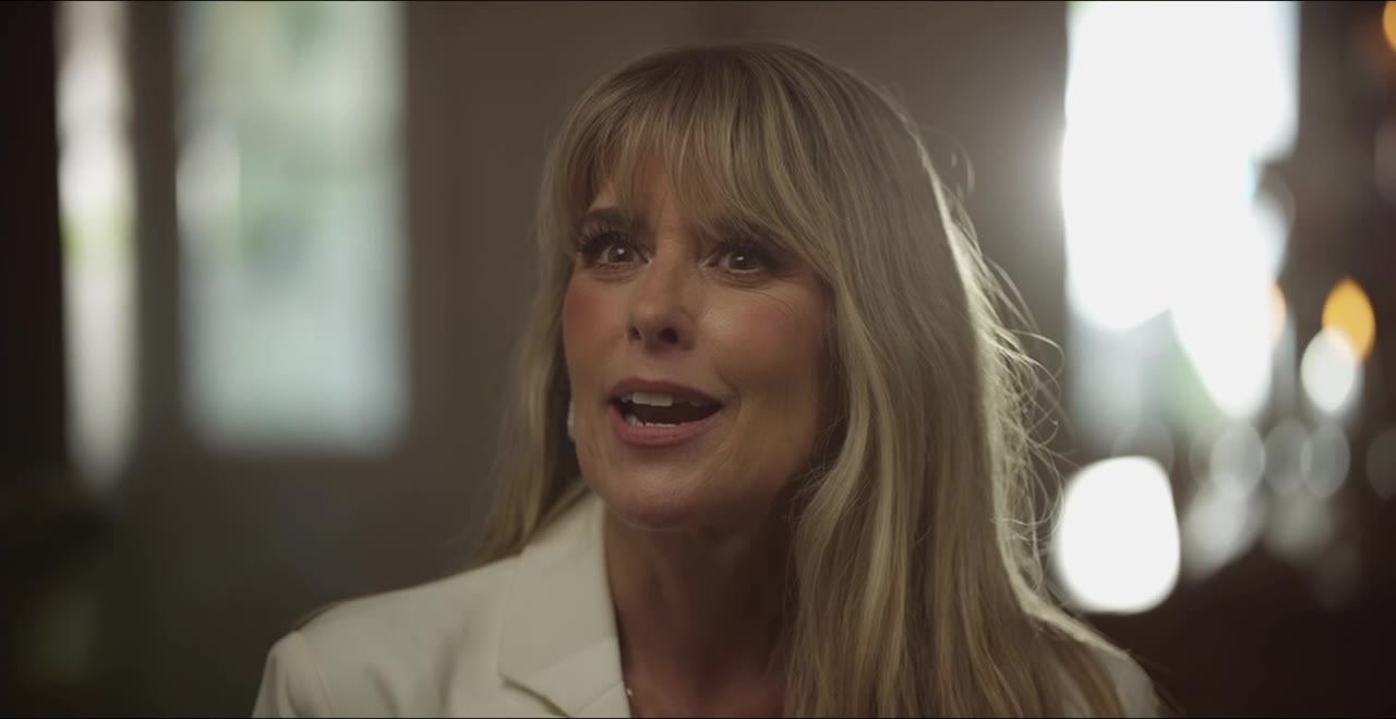 Charlene Byars in a documentary interview in the hallway of the house, window light behind her.
