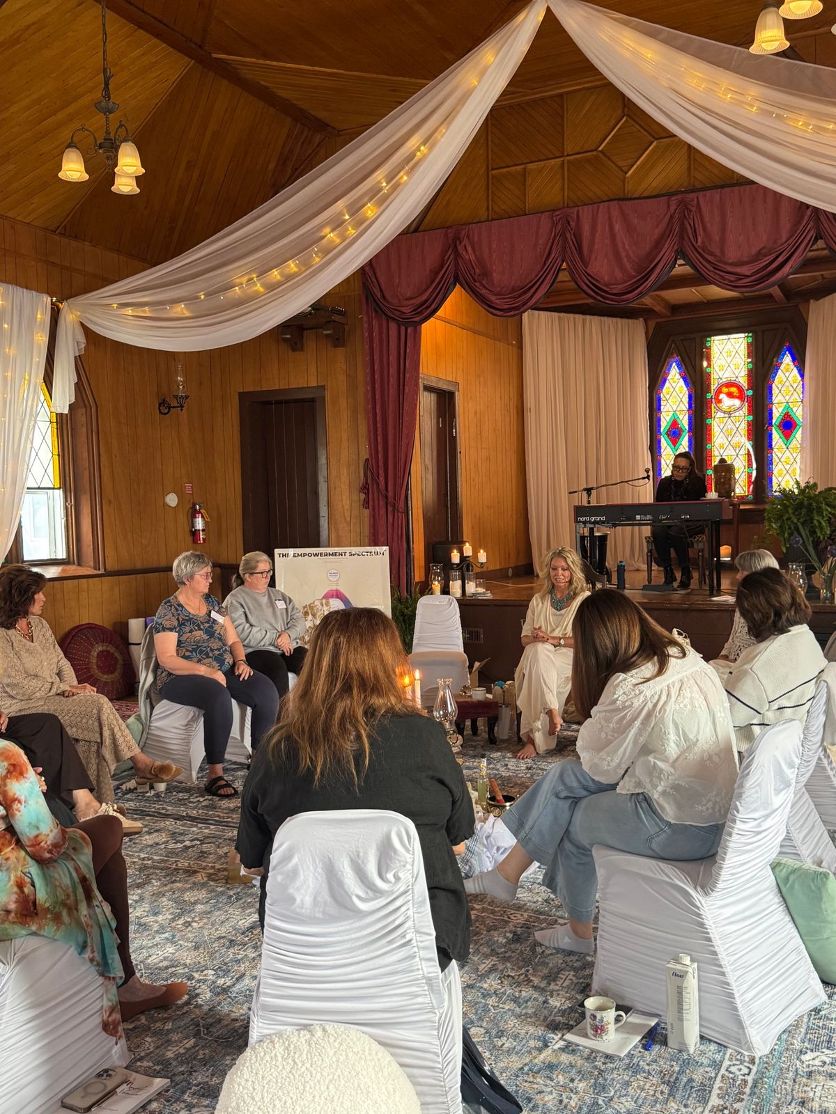 Crystal seated barefoot in the circle of women, a musician at the keyboard beneath the stained glass.