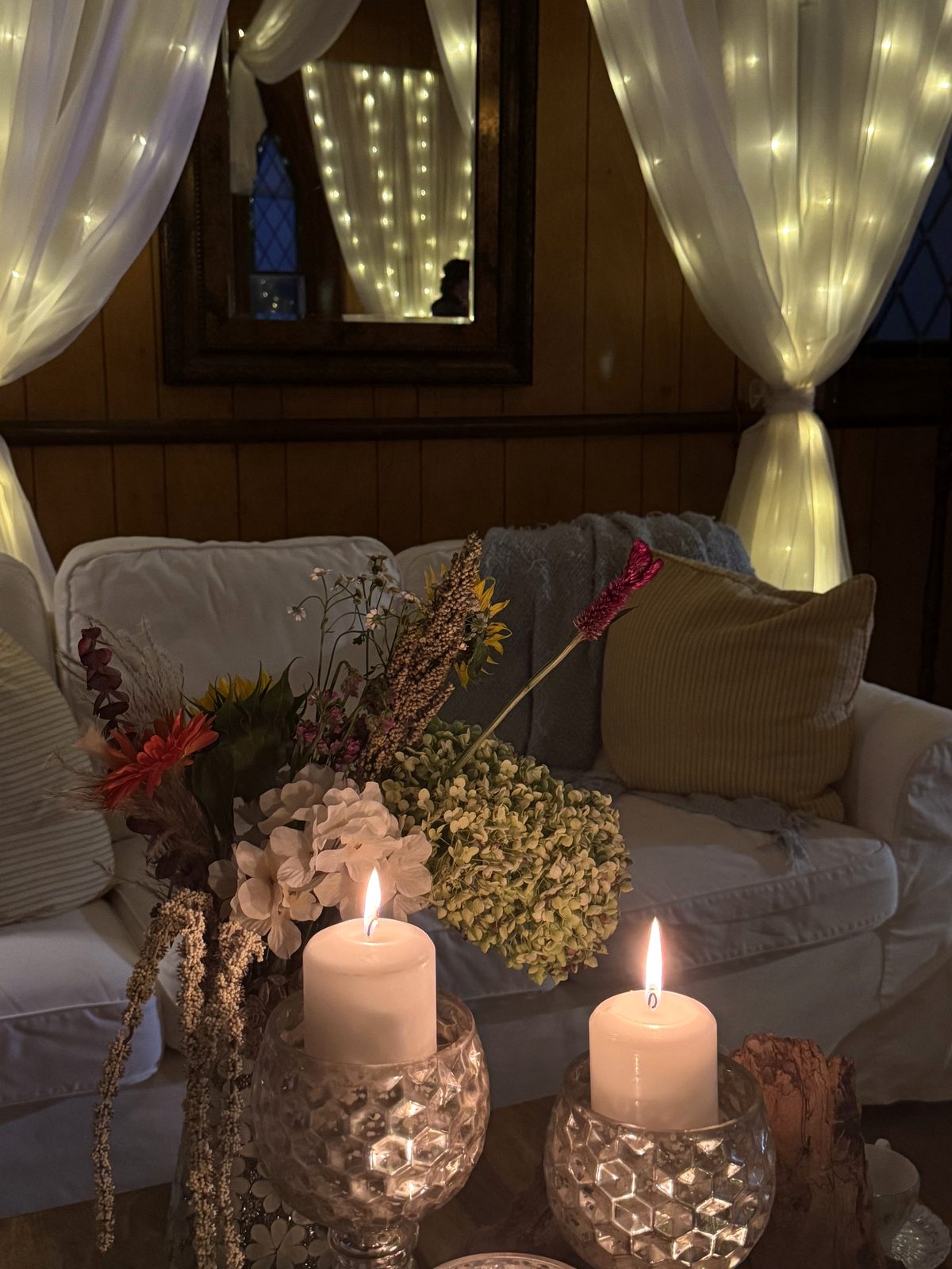 A quiet corner of the retreat house — candlelight, dried flowers, soft draping